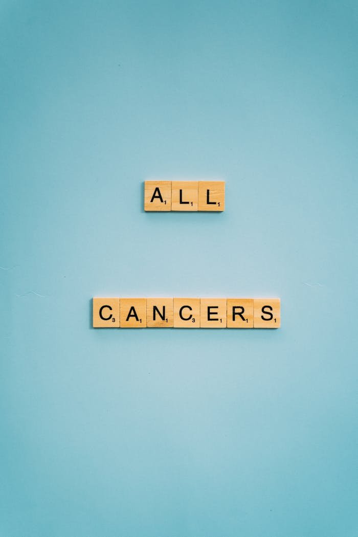 Scrabble tiles spelling All Cancers on a blue background emphasizing awareness.