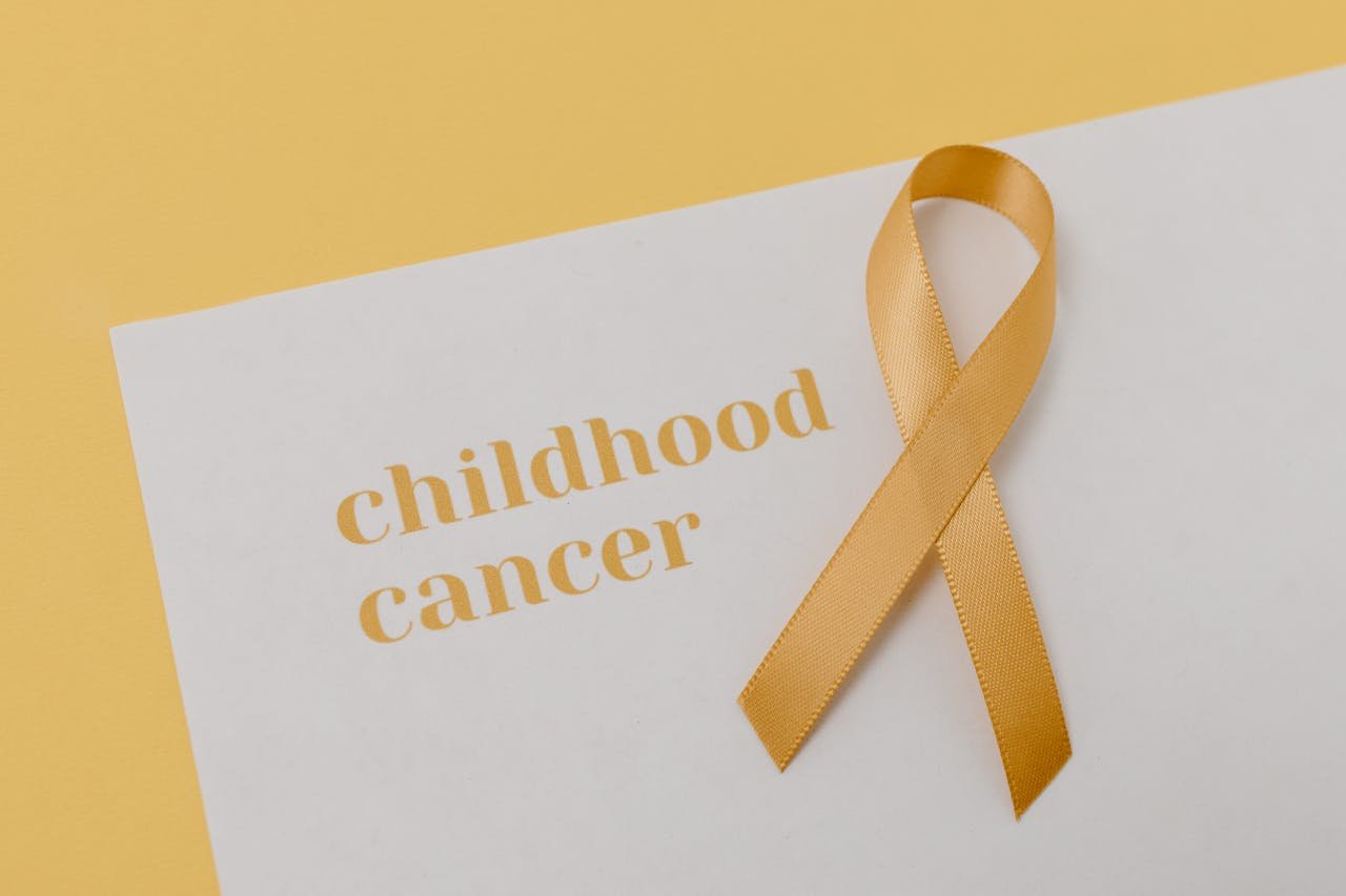 Gold ribbon symbolizing support for childhood cancer on a minimalist background